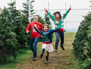 family jumping mid-air in a christmas tree lot