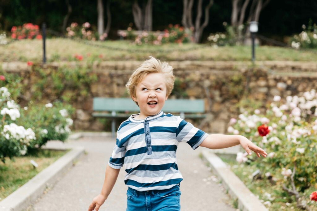 Young boy running with a goofy expression at the Morcom Rose Garden
