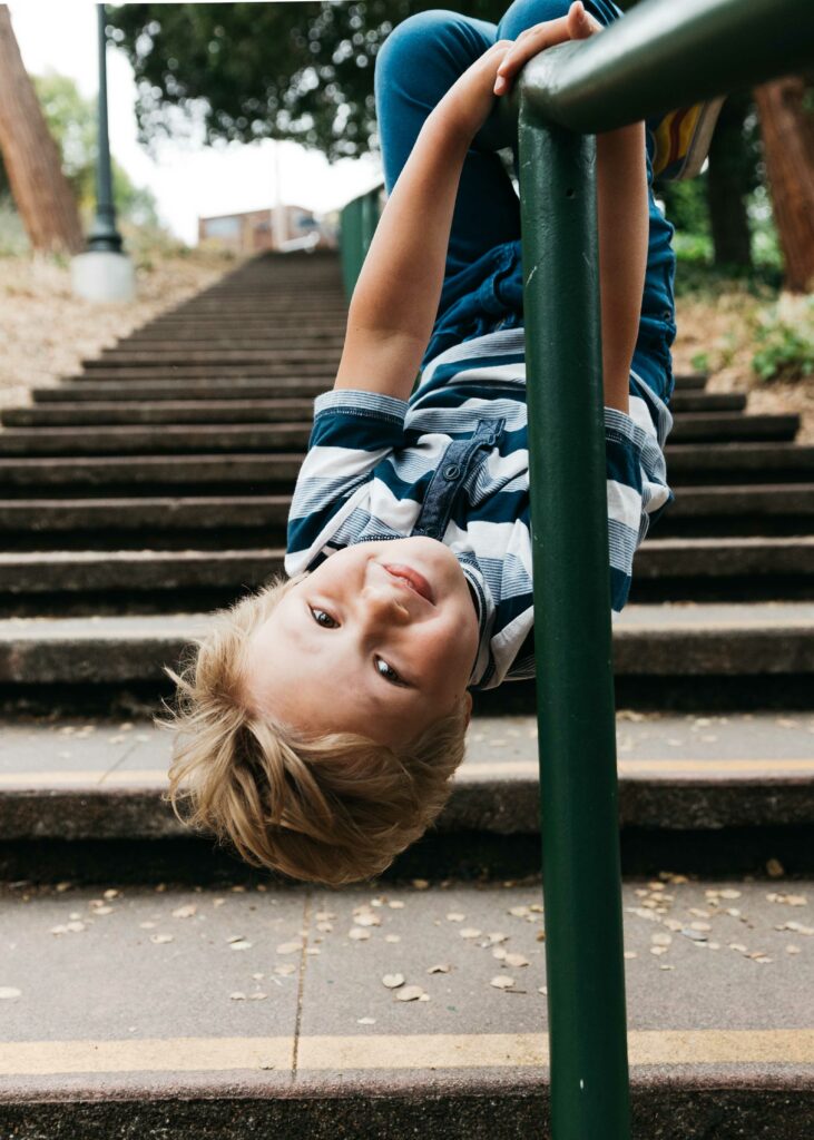 Young boy hanging upside down on the handrail at the Morcom Rose Garden