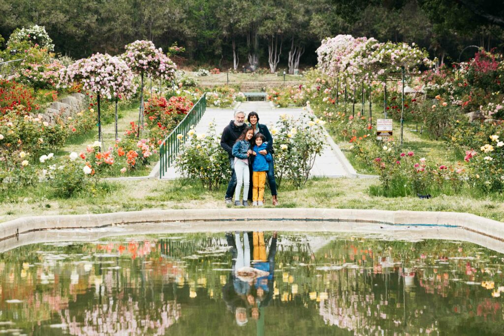 Family standing near the reflecting pond at the Morcom Rose Garden.