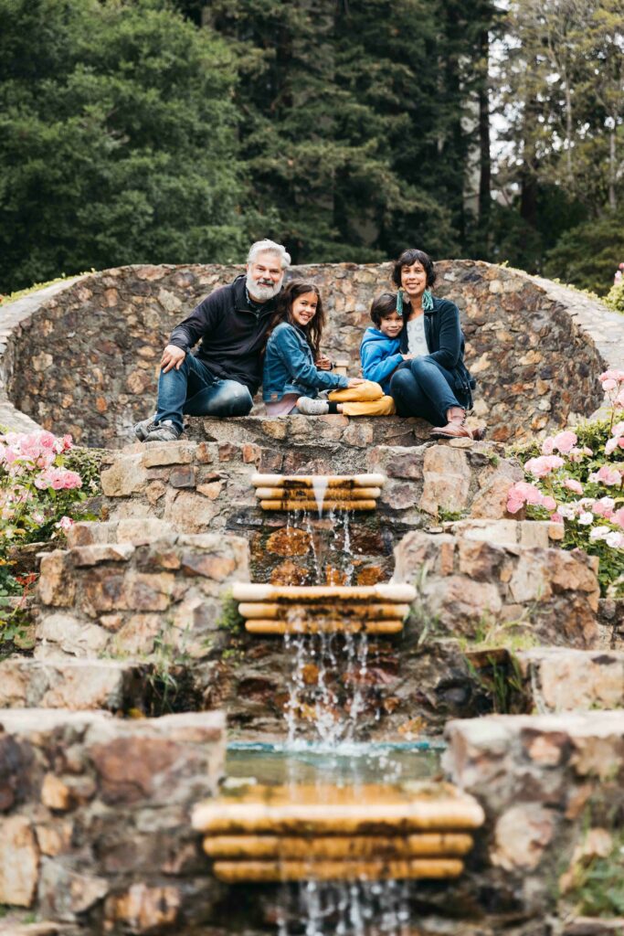 Family sitting at the top of the tiered fountain at the Morcom Rose Garden