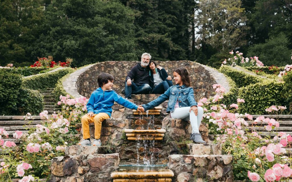 Family sitting at the top of the tiered fountain at the Morcom Rose Garden.