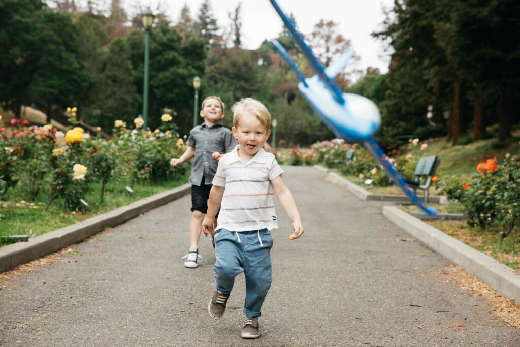Young brothers throwing toy airplanes at the Morcom Rose Garden