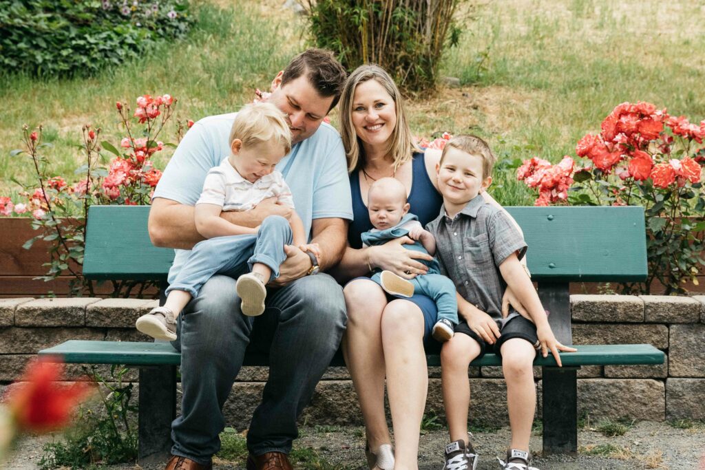 Family sitting on a bench near roses at the Morcom Rose Garden