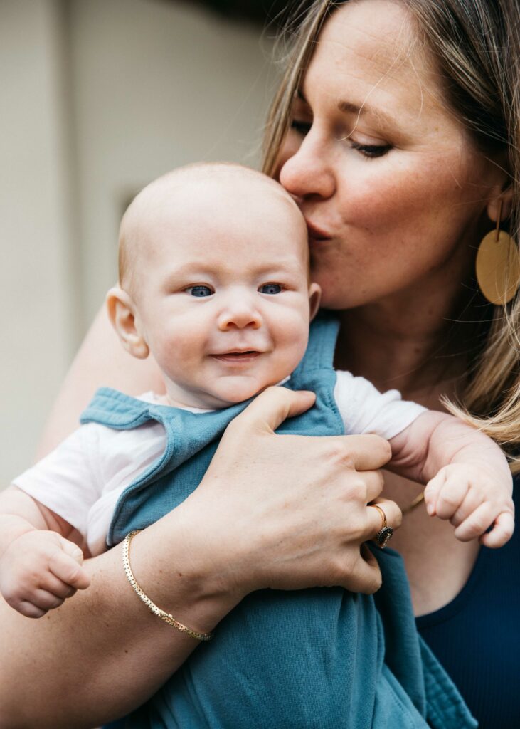 Mom kissing newborn son on the head.