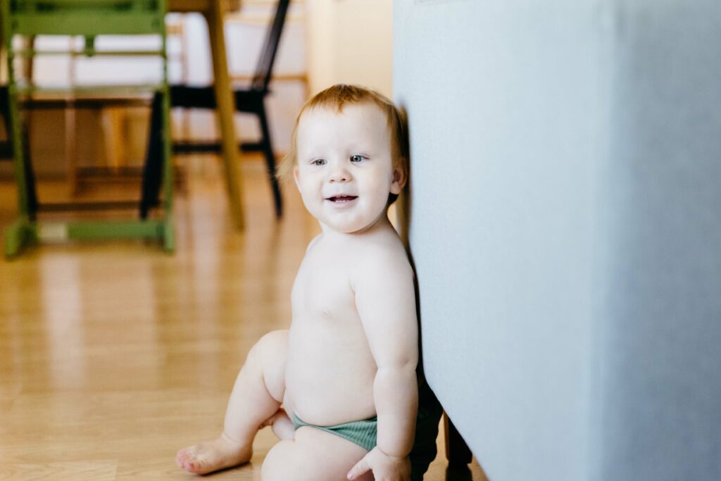 Toddler son leaning up against the sofa as he takes a break from crawling.