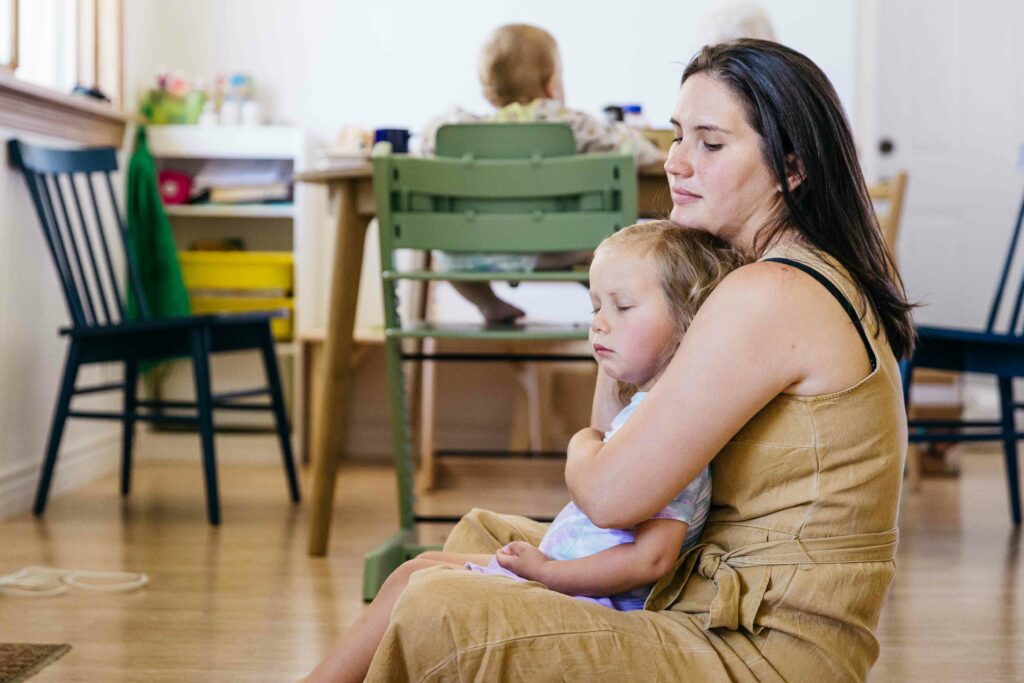 Mother holding grumpy son as he wakes up from a mid-afternoon nap.