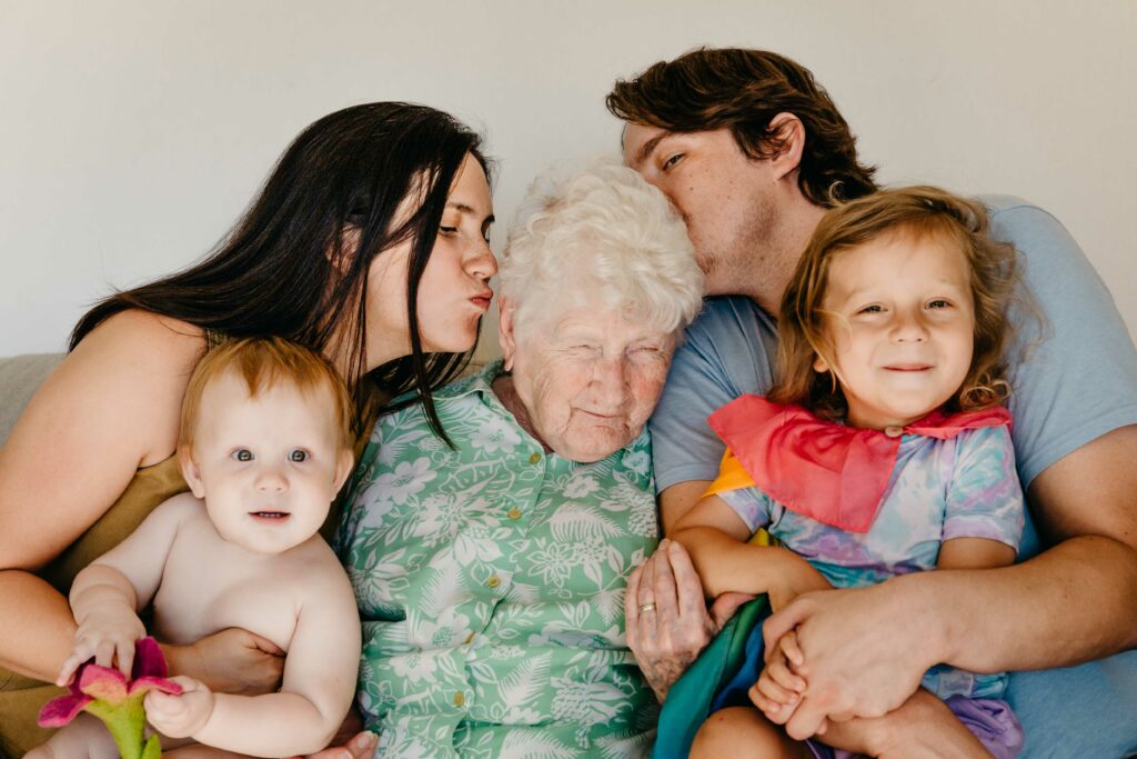 Family cuddling with grandma on the living room sofa