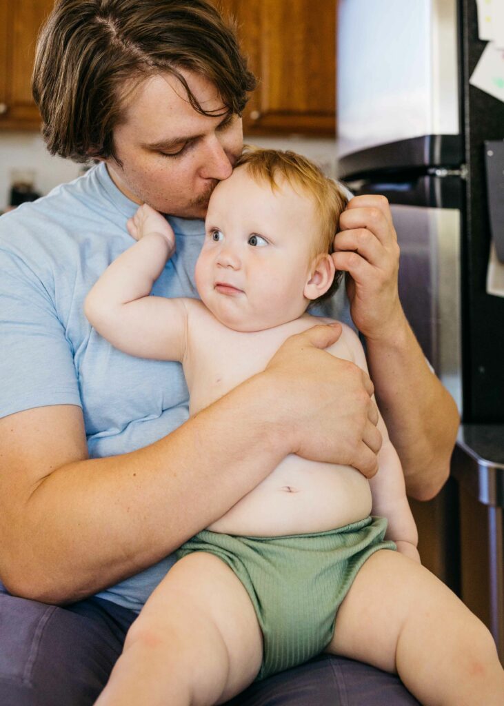 father and son cuddling at the kitchen table.
