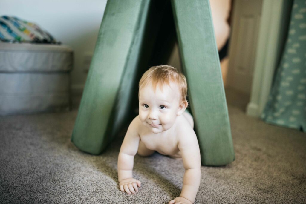 toddler boy crawling through seat cushions