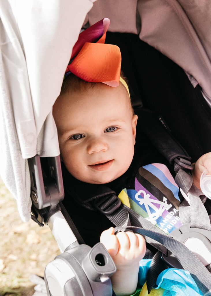 Young baby smiling from stroller at Alameda Pride