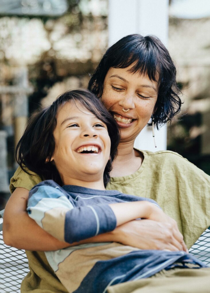 Mother hugging son in the backyard and laughing