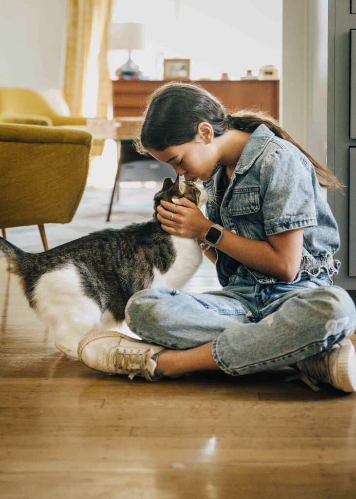 Girl kissing her pet cat on the head.