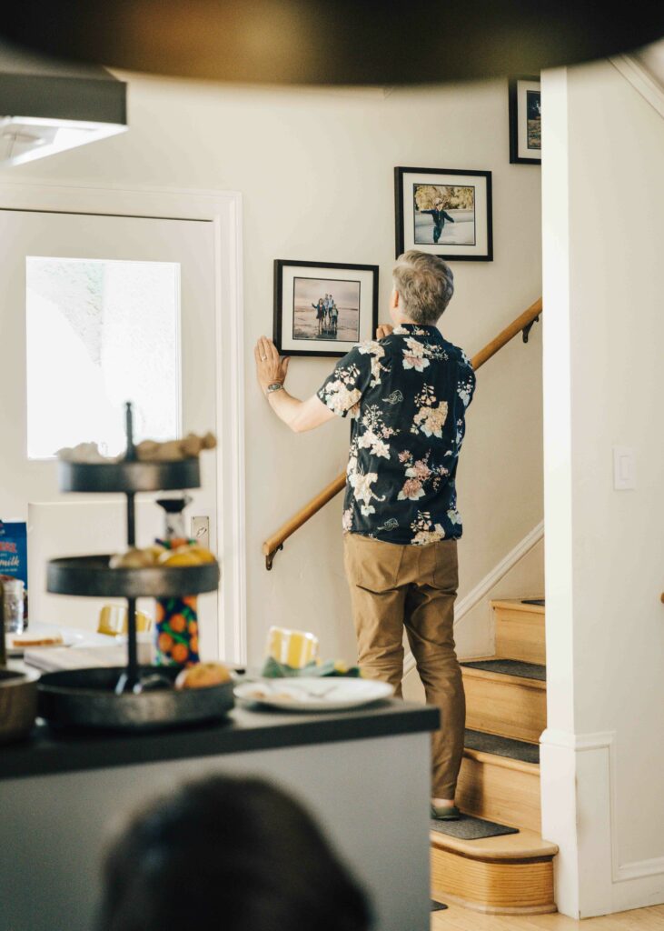 Man straightening photo frames on the wall.
