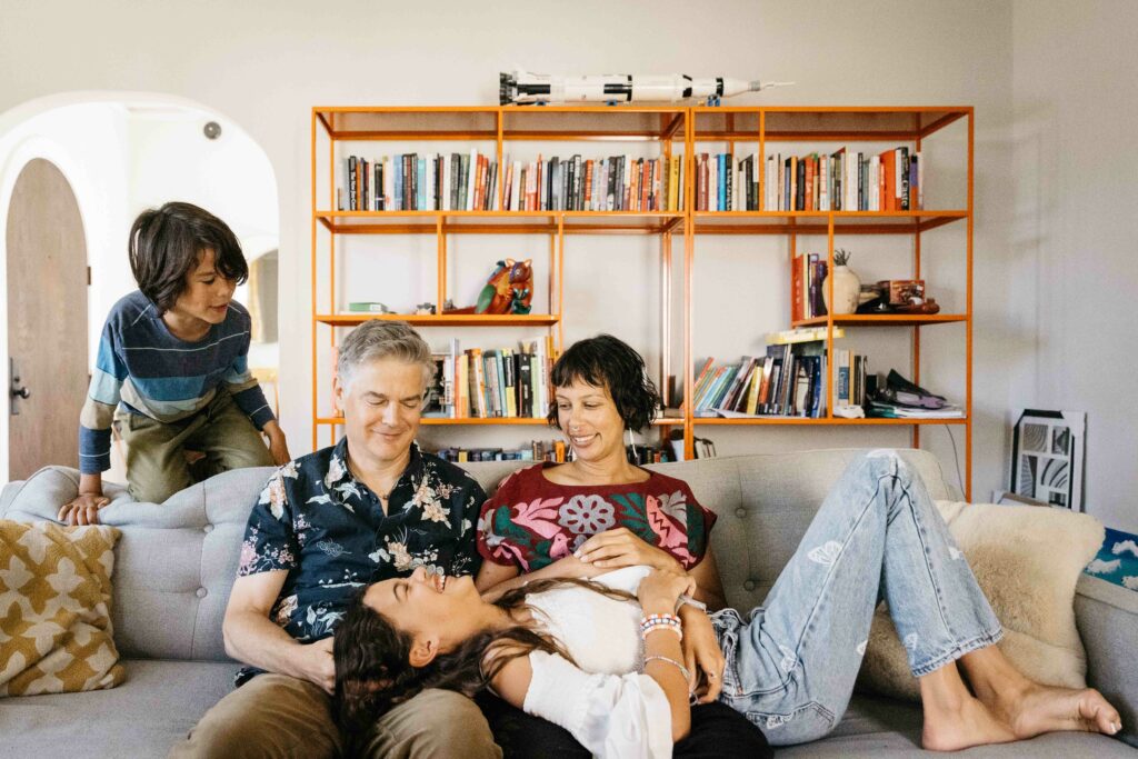 Family snuggling and laughing on the living room couch during an in-home photo session.