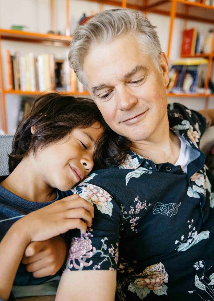 Father and son snuggling in the living room sofa.