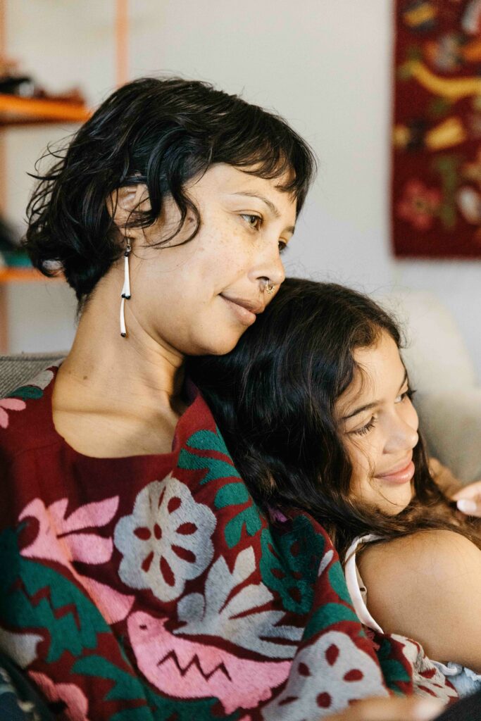 Mother and pre-teen daughter snuggling on the sofa.