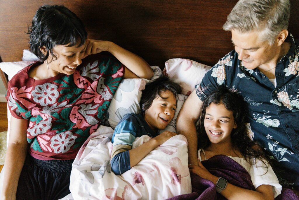 Family cuddled up in the bed.