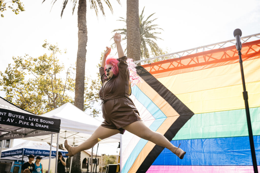Drag diva jumping in the air performing at Alameda Pride