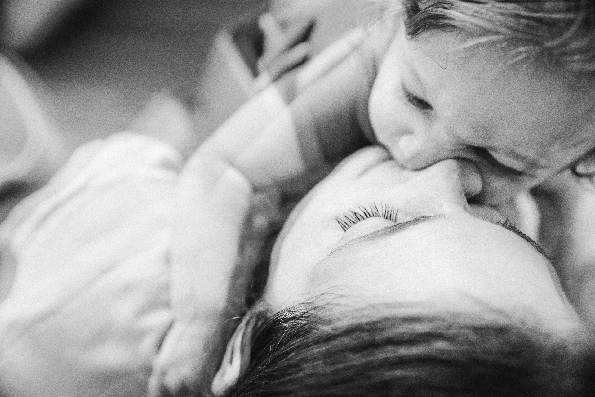 black and white double exposure image of mother kissing son