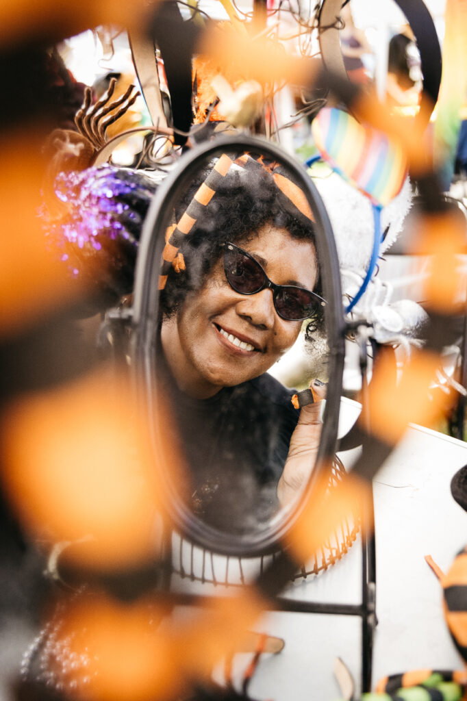 Woman vendor wearing spider hat at Alameda Pride