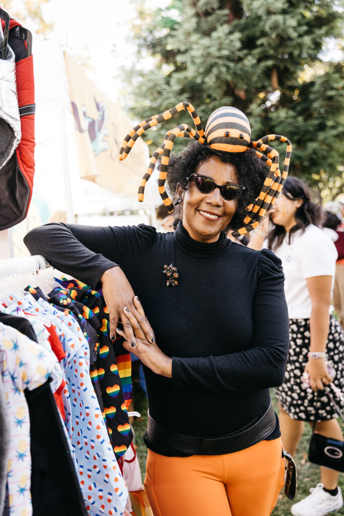 Woman vendor wearing spider hat at Alameda Pride