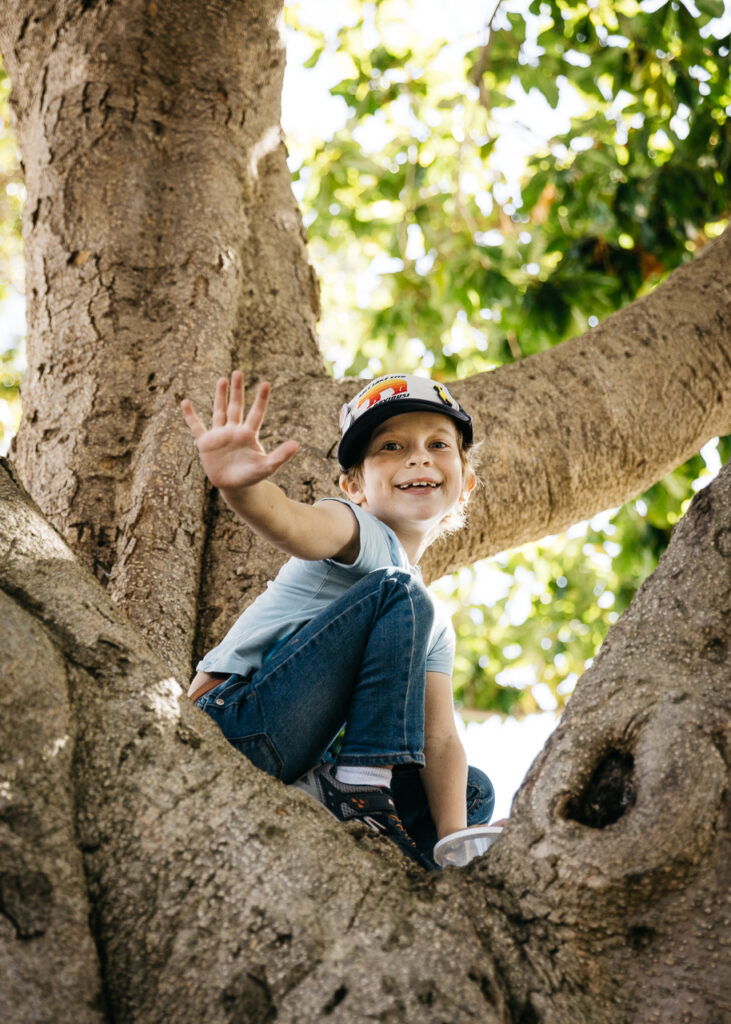 Young boy waving hello from tree branches at Alameda Pride