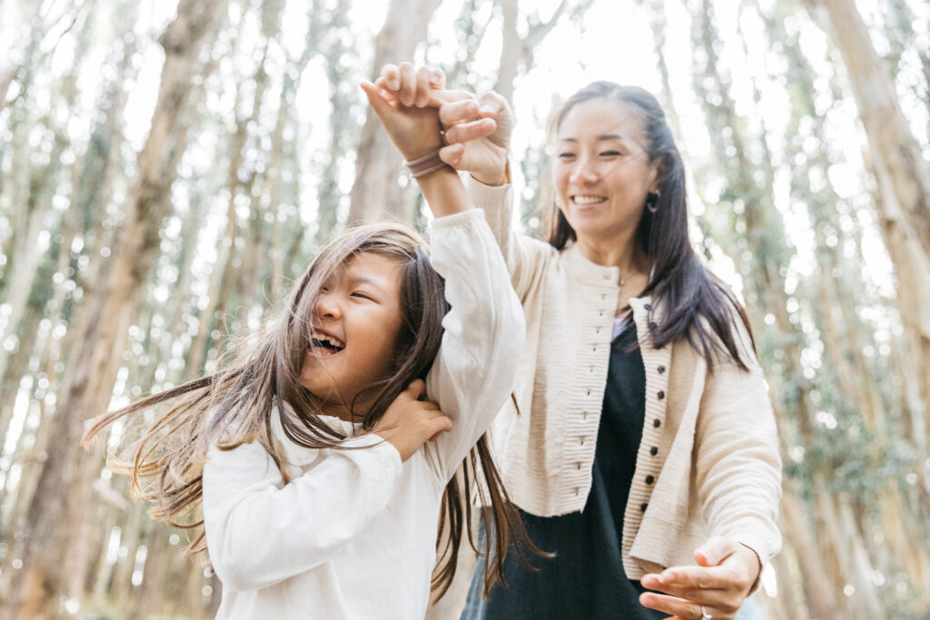 Mother and daughter laughing and dancing during a family photo session in the Presidio.