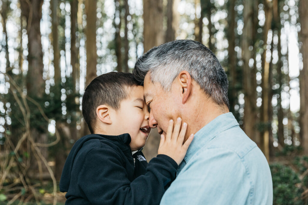 Dad and young son is sharing a nose kiss during a family photo session in the Presidio