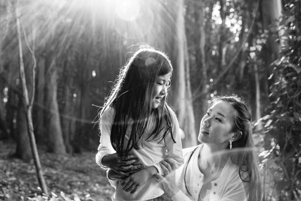 A black and white photo of a mother and young daughter connecting in the Presidio