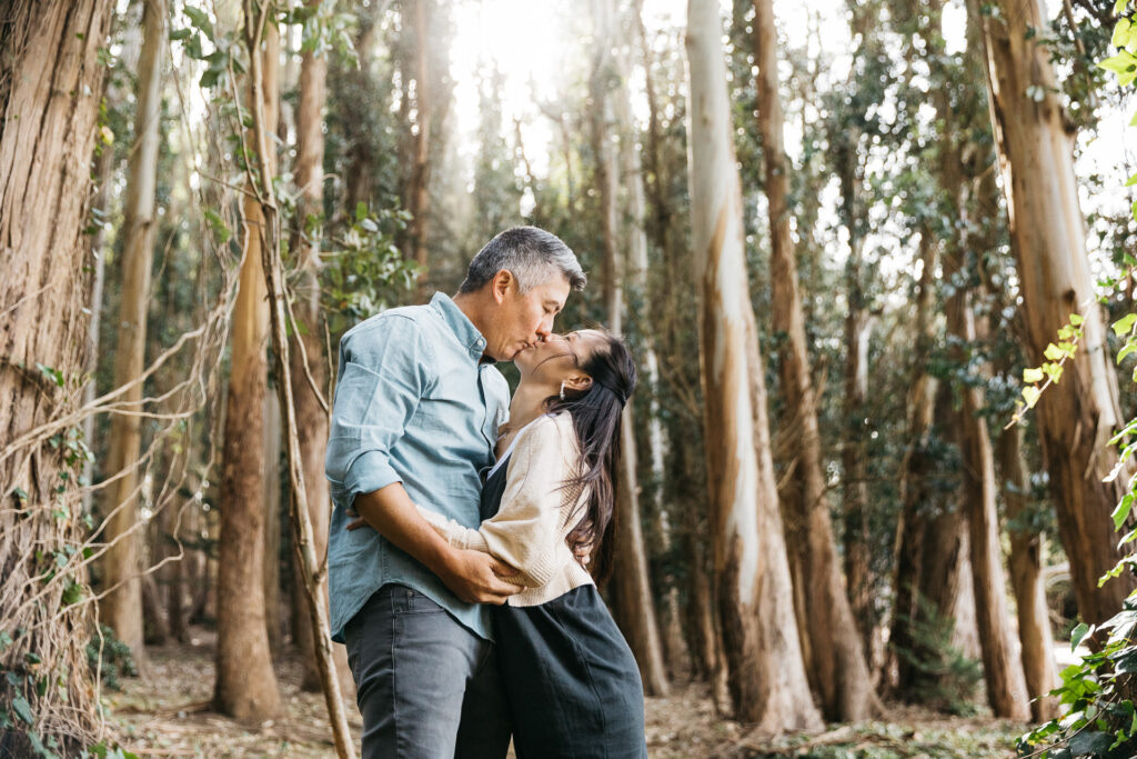Mom and dad sharing a kiss during a family photo session at Wood Line in the Presidiio
