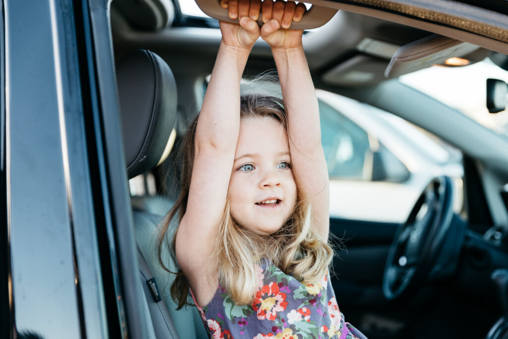 young girl swinging from the car during a family photo session in san francisco.