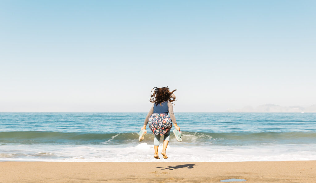 young girl jumping the waves at baker beach.