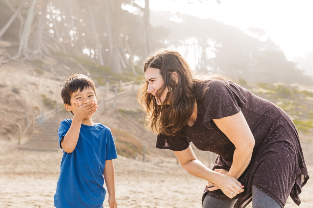 young boy laughing with his mom at baker beach.
