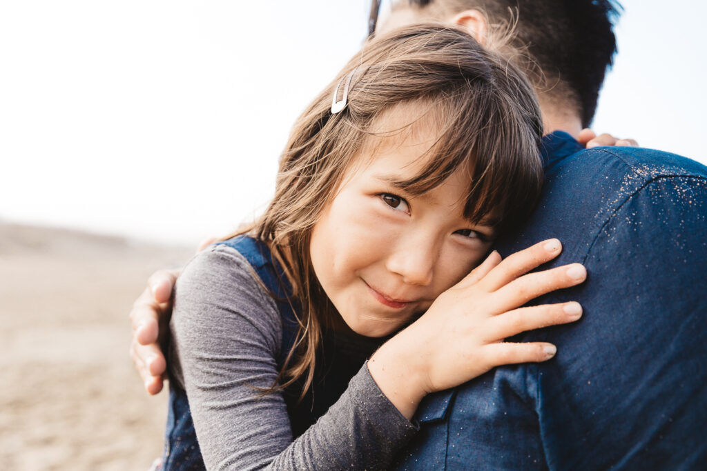 girl cuddling with dad at baker beach.