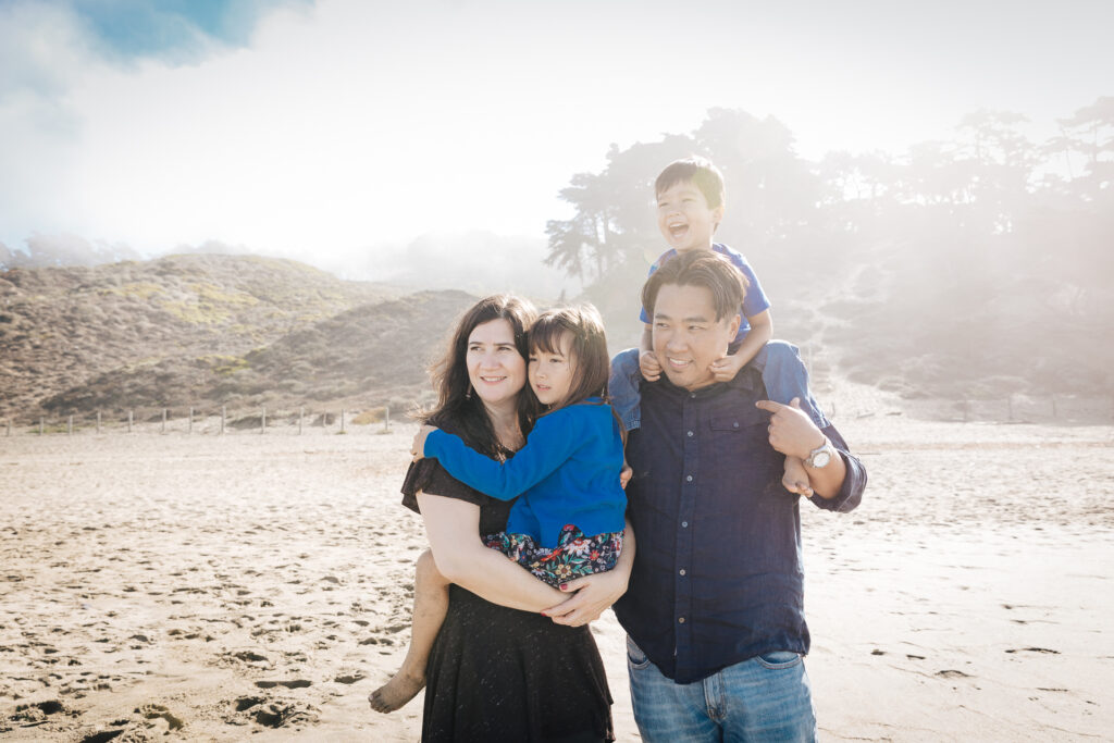 family standing and holding each other at baker beach.