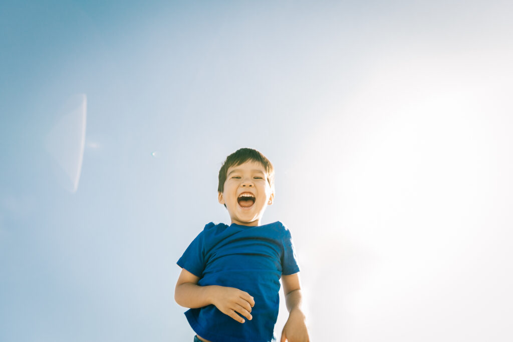 young son laughing while being tossed in the air by dad during a family photo session.