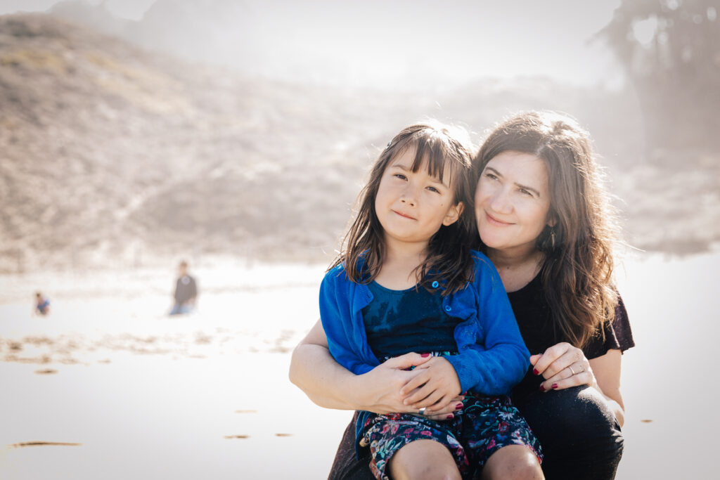 daughter sitting on mom's lap during a family photo session at baker beach.