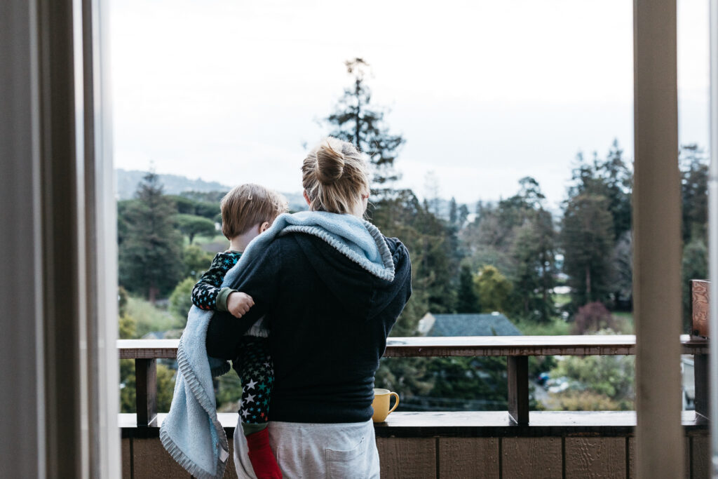 mom holding toddler son on a balcony during a family in-home photo session in oakland.