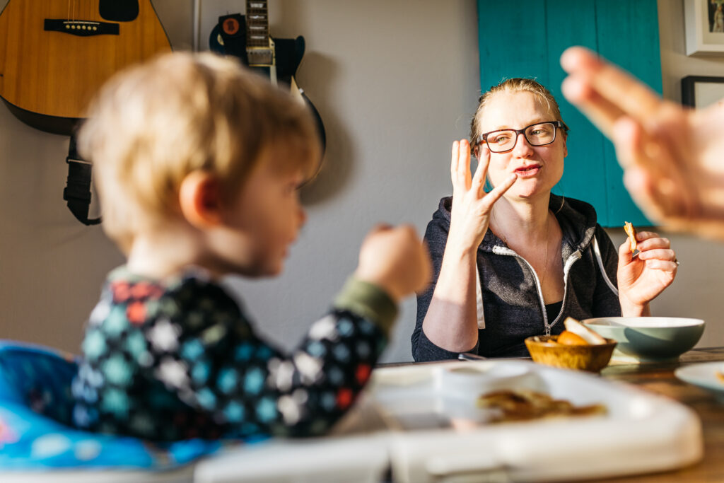 mom playing with toddler son at the breakfast table during a family photo session.