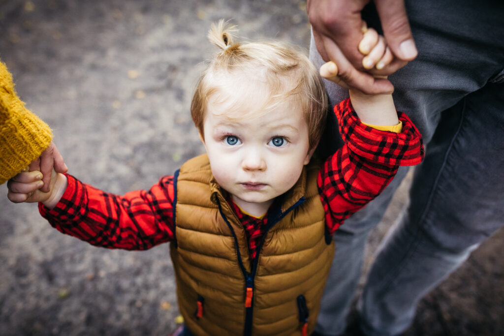 young boy holding his parent's hand during a family walk in oakland.
