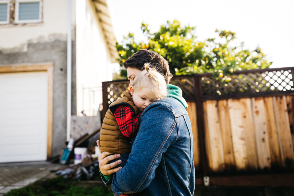 dad tenderly carrying son while walking in their oakland neighborhood.