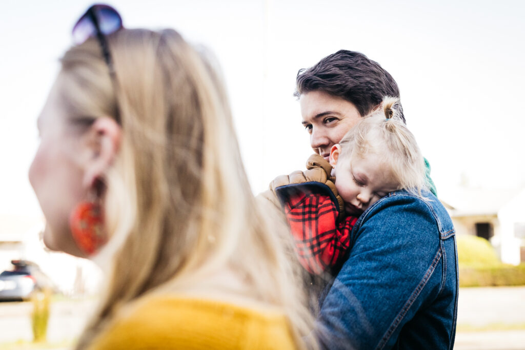 dad looking sweetly at wife while holding his son on a family walk.