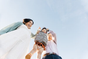 pregnant mom and husband swinging toddler girl during a maternity photo session.