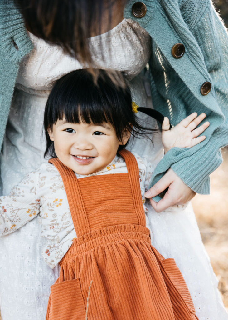Mother is playing peek-a-boo with her toddler daughter.