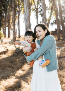 Expectant mom is laughing and holding her toddler daughter during a maternity session at Coyote Point.