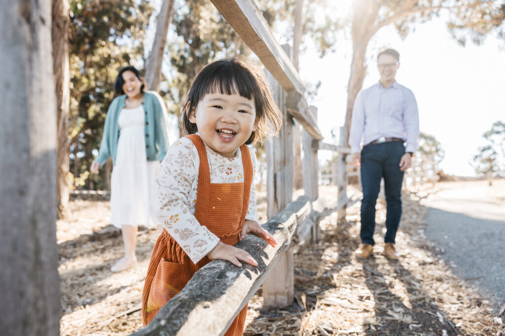 Toddler girl and family are all smiles as they play at Coyote Point park.