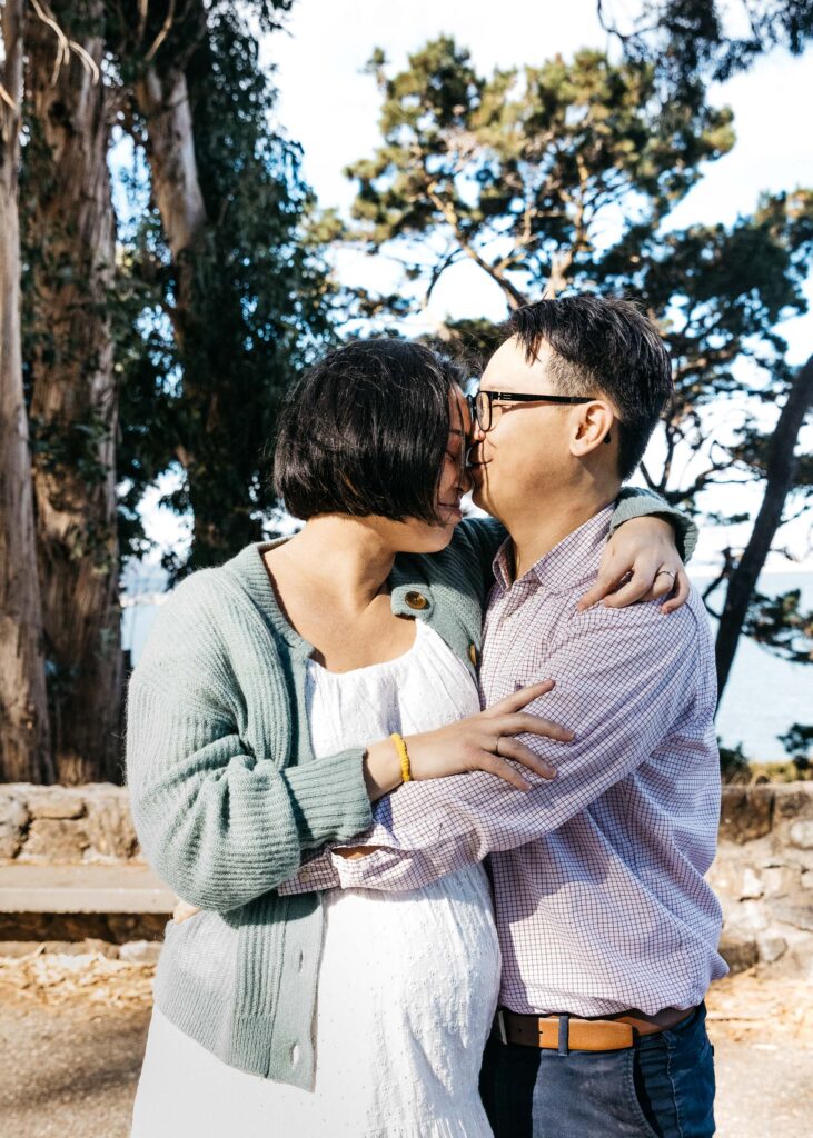 Mother and father sharing a tender moment as they hug and kiss at Coyote Point.