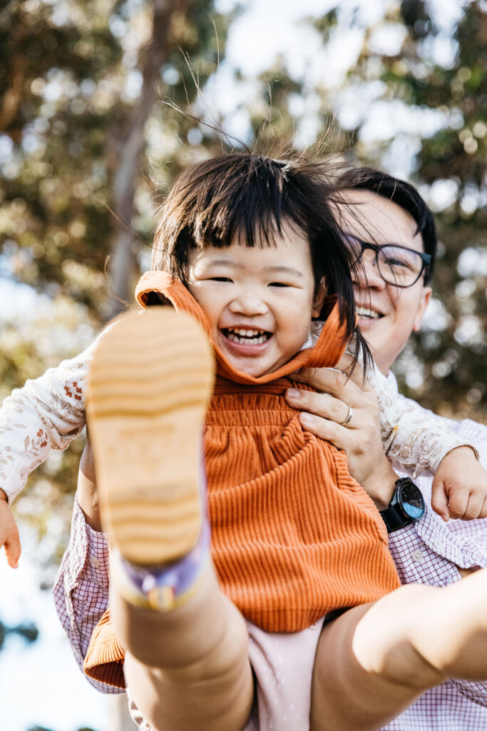 Dad tossing toddler daughter during a family photo session.