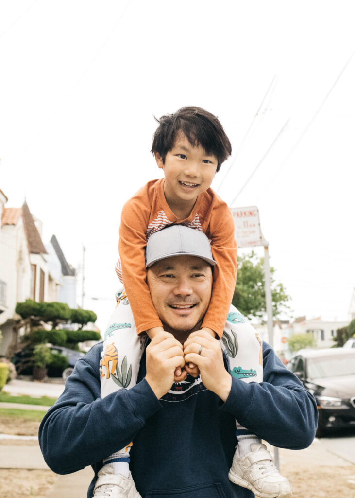 dad carrying toddler son on his shoulders in san francisco during a family photo session.